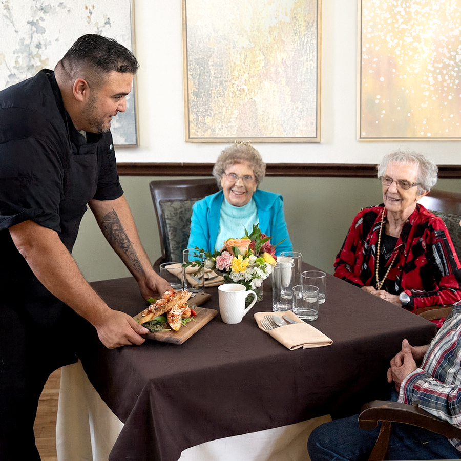 The chef brings out the appetizers to a table of residents at ATrium